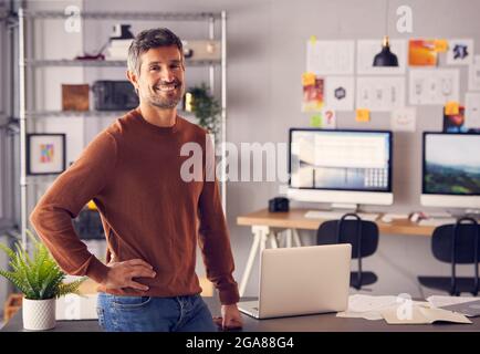 Portrait Of Mature Male Advertising Marketing Or Design Creative In Studio Standing By Desk Stock Photo