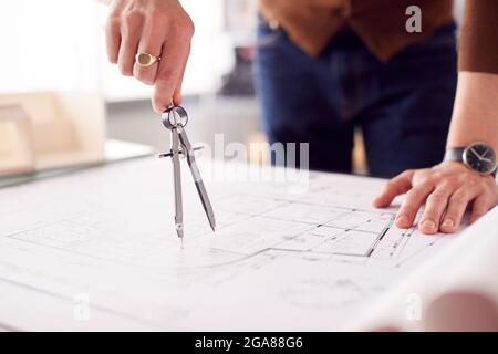 Close Up Of Male Architect In Office Measuring Plan Or Blueprint Using Dividers Stock Photo