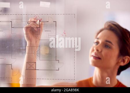 Female Architect In Office Making Notes On Building Blueprint On Transparent Screen Stock Photo