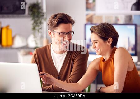 Male And Female Architects In Office Working At Desk On Laptop And Looking At Plans Stock Photo