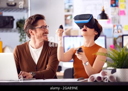 Female Architect Wearing VR Headset In Office Working With Male Colleague At Desk With Laptop Stock Photo