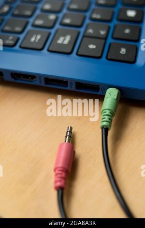 Earphones cables connected to a blue modern laptop on a wooden table Stock Photo