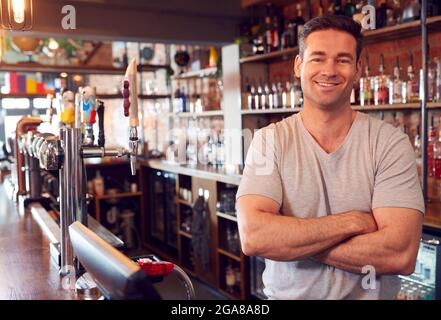Portrait Of Smiling Male Bar Owner Standing Behind Counter Stock Photo
