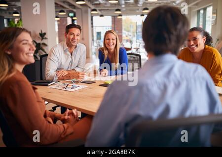 Business Team Having Meeting Sitting Around Table In Modern Open Plan Office Stock Photo