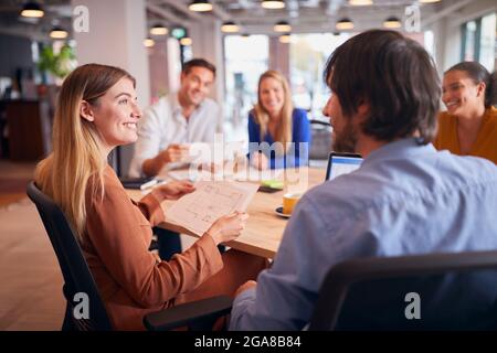 Business Team Having Meeting Sitting Around Table In Modern Open Plan Office Stock Photo