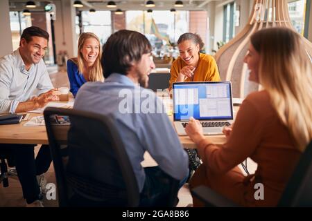 Business Team Having Meeting Sitting Around Table In Modern Open Plan Office Stock Photo