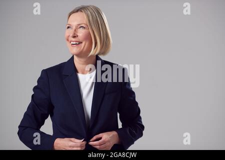 Studio Portrait Of Smiling Mature Businesswoman Against Plain Background Stock Photo
