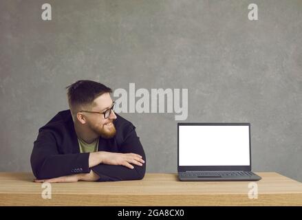 Happy young man looking at blank white mockup screen of his modern laptop computer Stock Photo
