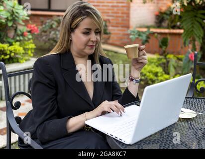 Young businesswoman drinking coffee while working outdoors Stock Photo