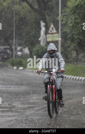 A cyclist seen riding along an empty and deserted road during a rainy day amid the covid-19 lockdown.The country went into a strict lockdown and Heavy monsoon downpour caused extreme water logging in most areas of Dhaka city. Roads were submerged making travel slow and dangerous. Stock Photo