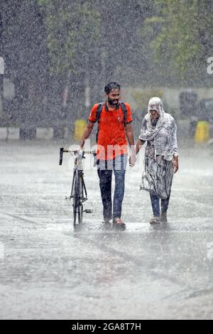 A couple seen walking along an empty and deserted road during a rainy day amid the covid-19 lockdown.The country went into a strict lockdown and Heavy monsoon downpour caused extreme water logging in most areas of Dhaka city. Roads were submerged making travel slow and dangerous. Stock Photo