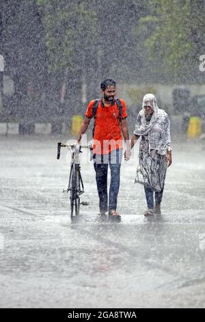 Dhaka, Bangladesh. 29th July, 2021. A couple seen walking along an empty and deserted road during a rainy day amid the covid-19 lockdown.The country went into a strict lockdown and Heavy monsoon downpour caused extreme water logging in most areas of Dhaka city. Roads were submerged making travel slow and dangerous. (Photo by Sazzad Hossain/SOPA Images/Sipa USA) Credit: Sipa USA/Alamy Live News Stock Photo