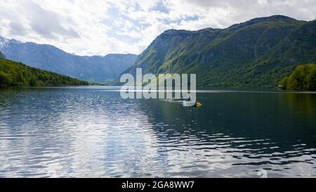 Aerial bird eye shot of a canoe with two person paddling, on beautiful turquoise lake water