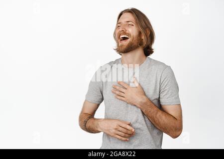 Attractive swedish man with stylish hair and beard laughs at funny story from friend with crossed hands and closed eyes Stock Photo