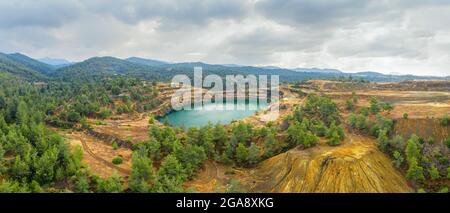 Restoration works in copper mining area with lake in open mine pit and spoil heaps covered with pine trees in Troodos mountains, Cyprus Stock Photo