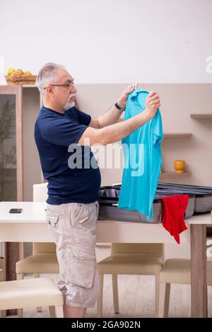 Old male tourist preparing for trip at home Stock Photo