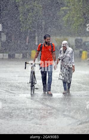 Dhaka, Bangladesh. 29th July, 2021. A couple seen walking along an empty and deserted road during a rainy day amid the covid-19 lockdown.The country went into a strict lockdown and Heavy monsoon downpour caused extreme water logging in most areas of Dhaka city. Roads were submerged making travel slow and dangerous. (Credit Image: © Sazzad Hossain/SOPA Images via ZUMA Press Wire) Stock Photo