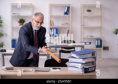 Old businessman employee unhappy with excessive work in the office Stock Photo