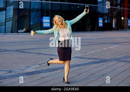 Cheerful female secretary dances near business center. Stock Photo