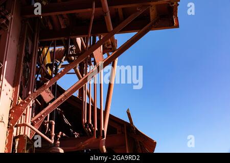 Blistered paint on heavy metal industrial structures, bright blue sky, horizontal aspect Stock Photo