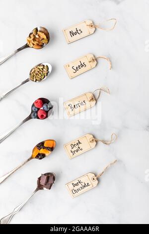 Various spoons filled with ingredients commonly used in making smoothie bowls or trail mix. Stock Photo