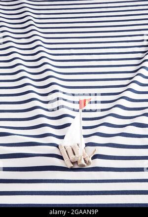 Wooden raft with a white sails on a sailor's shirt instead of the sea. Rectangle layout. Stock Photo