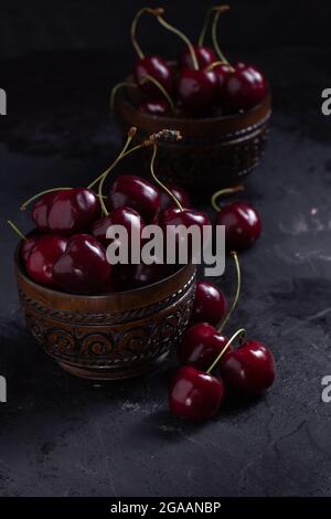 Organic juicy cherry in a bowl on dark background. Close-up photo, low key Stock Photo