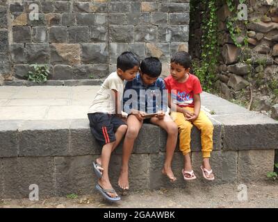 17 July 2021, Maharashtra, India, Little Indian kids playing with cellphone. Stock Photo