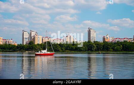 Panorama of Kyiv city scape of Dnipro River. Modern residential building, yacht and park with urban street landscape by the river. Stock Photo