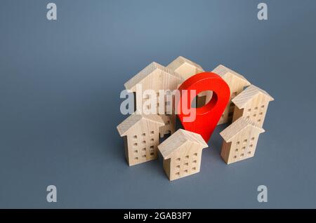 Wooden houses and a red location pin. Location, accessibility to infrastructure. Residential complex. City navigation, orienteering. Search for housin Stock Photo