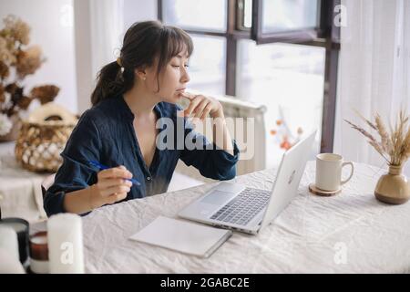 Busy focused asian woman freelancer working remotely on laptop from home, remotely working concept Stock Photo