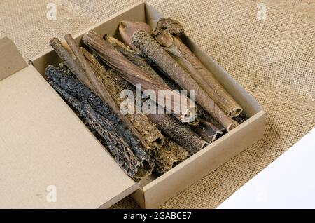 Full Cardboard Pet Treat Box on burlap fabric. Dried dog goodies. Tasty Beef Tripe Sticks. Bovine stomach. Selective focus Stock Photo