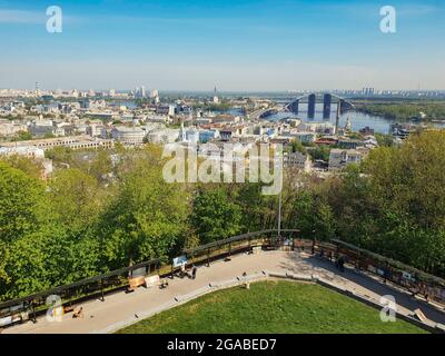 Kiev, Ukraine-April 29, 2018: Beautiful scenery of Dnieper River and the bridge from St. Andrew's Cathedral's top. Street painters displaying and sell Stock Photo