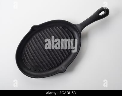 From above of empty clean oval shaped black iron cast grill skillet on white background Stock Photo