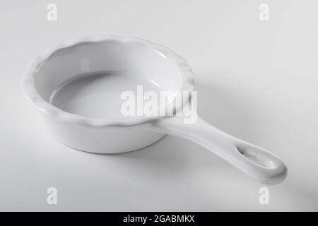 High angle of empty round shaped white ceramic baking dish with handle on white background Stock Photo