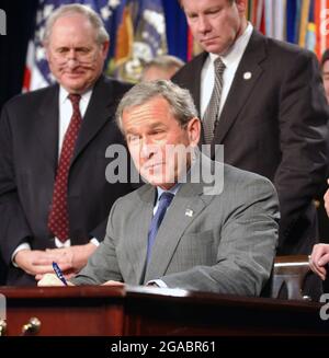 Arlington, United States Of America. 05th Oct, 2001. United States President George W. Bush signs H.R. 1588, the National Defense Authorization Act of Fiscal Year 2004 at the Pentagon in Arlington, Virginia on November 24, 2003. United States Senator Carl Levin (Democrat from Michigan), the ranking member of the Senate Armed Services Committee, left, and United States Representative Tom Davis (Republican of Virginia), right, look on.Credit: Ron Sachs/CNP/Sipa USA Credit: Sipa USA/Alamy Live News Stock Photo