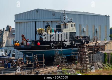 girvan shipyard, girvan boatyard, tugboat, girvan harbour, girvan dry dock, girva, repair slipway, boat repair yard in ayrshire, tug out of water. Stock Photo