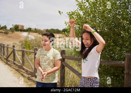 MOSTOLES, SPAIN - May 22, 2021: Children playing laughing happily in a park with wooden fence behind them Stock Photo