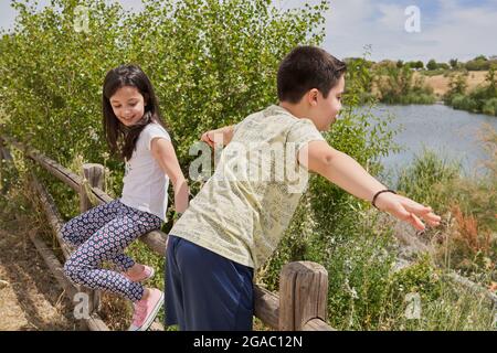 MOSTOLES, SPAIN - May 22, 2021: Happy children playing laughing climbed on a wooden fence in a park Stock Photo