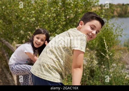 MOSTOLES, SPAIN - May 22, 2021: Happy children playing laughing climbed on a wooden fence in a park Stock Photo