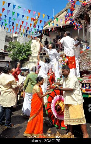 A busy street scene in Penang Malaysia during a Thaipusam procession. The floats are pulled by decorated bulls and devotees smash coconuts Stock Photo