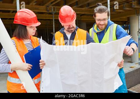 Architect and craftsman team with construction drawing on a new construction site during construction planning Stock Photo