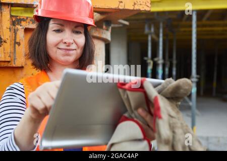 Architect with tablet computer uses app to plan the construction project on the construction site in the shell Stock Photo
