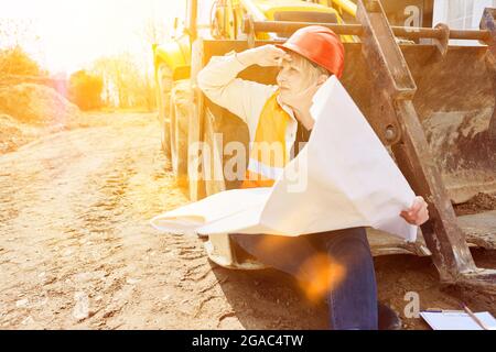Woman as a construction worker building house sits on shovel from excavator at break Stock Photo