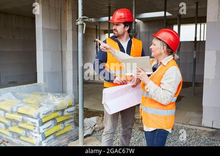 Architect with tablet computer on a construction site during construction planning with the foreman Stock Photo