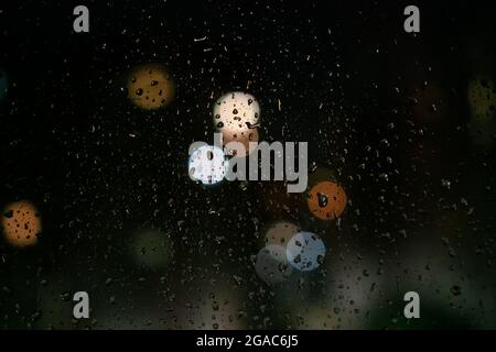 Water drops, city lights on the glass at night, bokeh, background Stock Photo