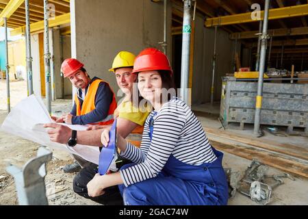 Architect and craftsman team with construction plan and checklist on the construction site in the shell Stock Photo