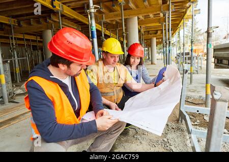 Team of craftsmen and architects with building drawings when building a house on the construction site Stock Photo