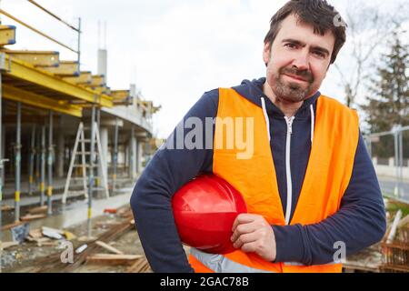 Craftsman or construction worker in protective clothing and with helmet on the construction site of the house building Stock Photo