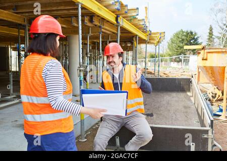 The architect and construction worker discuss the construction project together on the shell of the construction site Stock Photo